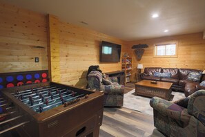 Ein gemütliches Zimmer mit Kicker, einer Ledersofa und einem Fernseher.