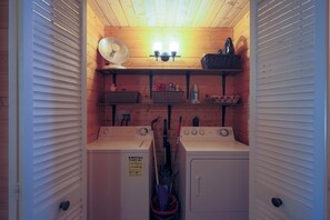 A laundry room with two washing machines, a dryer, a fan, and shelves with baskets and cleaning supplies. - Luxury Cottage w/NEW HOT TUB near National Parks and Loaded with Amenities (Duck Creek Village)