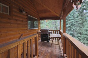 A wooden deck with a grill and a table, surrounded by trees. - Luxury Cottage w/NEW HOT TUB near National Parks and Loaded with Amenities (Duck Creek Village)