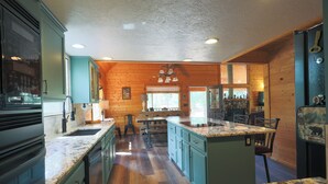 A kitchen with wooden walls, a central island, and a built-in oven. - Luxury Cottage w/NEW HOT TUB near National Parks and Loaded with Amenities (Duck Creek Village)