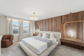 Une chambre moderne avec un grand lit, un mur d’accent en bois et une vue sur l’extérieur.
