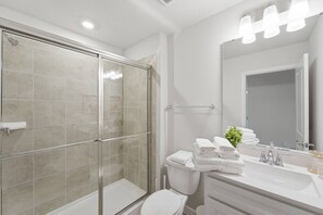 Une salle de bain moderne avec une douche à parois de verre, des toilettes blanches et un meuble-lavabo avec un miroir.