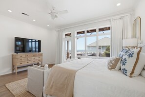 Une chambre à coucher avec un lit, une télévision, un ventilateur de plafond et une vue sur l’extérieur.