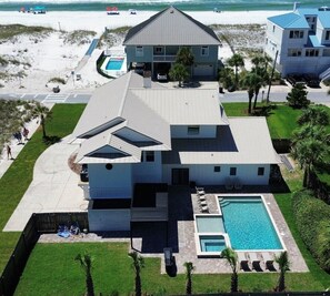 A two-story house with a swimming pool, a covered patio, and a view of the beach. - Newly Remodeled Designer's Luxury BeachHome/Amazing views,POOL,10 steps to sand! (Pensacola Beach)