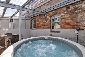 Ein Whirlpool in einem überdachten Außenbereich mit Backsteinmauern und einer Pergola.