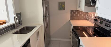 Una cocina moderna con electrodomésticos de acero inoxidable, lavavajillas y microondas.