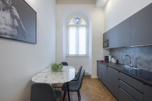 A modern kitchen with grey cabinets, a marble countertop, and a built-in oven. - Florence Central Bright Stay - Near the Duomo (Florence)