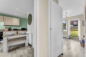 Une cuisine moderne avec un banc intégré, une horloge et une vue sur le jardin grâce à la porte ouverte.