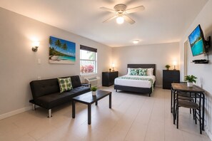 Ein modernes Zimmer mit Bett, Sofa, Esstisch und Fernseher.