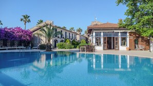 A pool with clear water, a building with a tiled roof, and a palm tree. - Aydos Hotels & Breeze Restaurant (Ortaca)