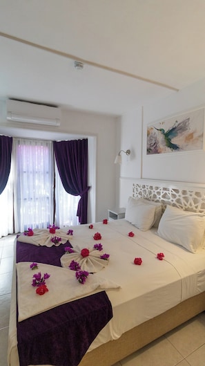 A hotel room with a large bed, a window with curtains, an air conditioning unit, a wall-mounted lamp, and a painting. - Aydos Hotels & Breeze Restaurant (Ortaca)
