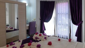 Una habitación de hotel con cama, espejo, escritorio y unidad de aire acondicionado.