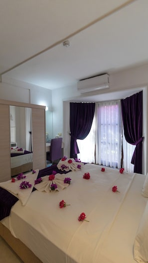 Una habitación de hotel con cama, espejo, escritorio y unidad de aire acondicionado.