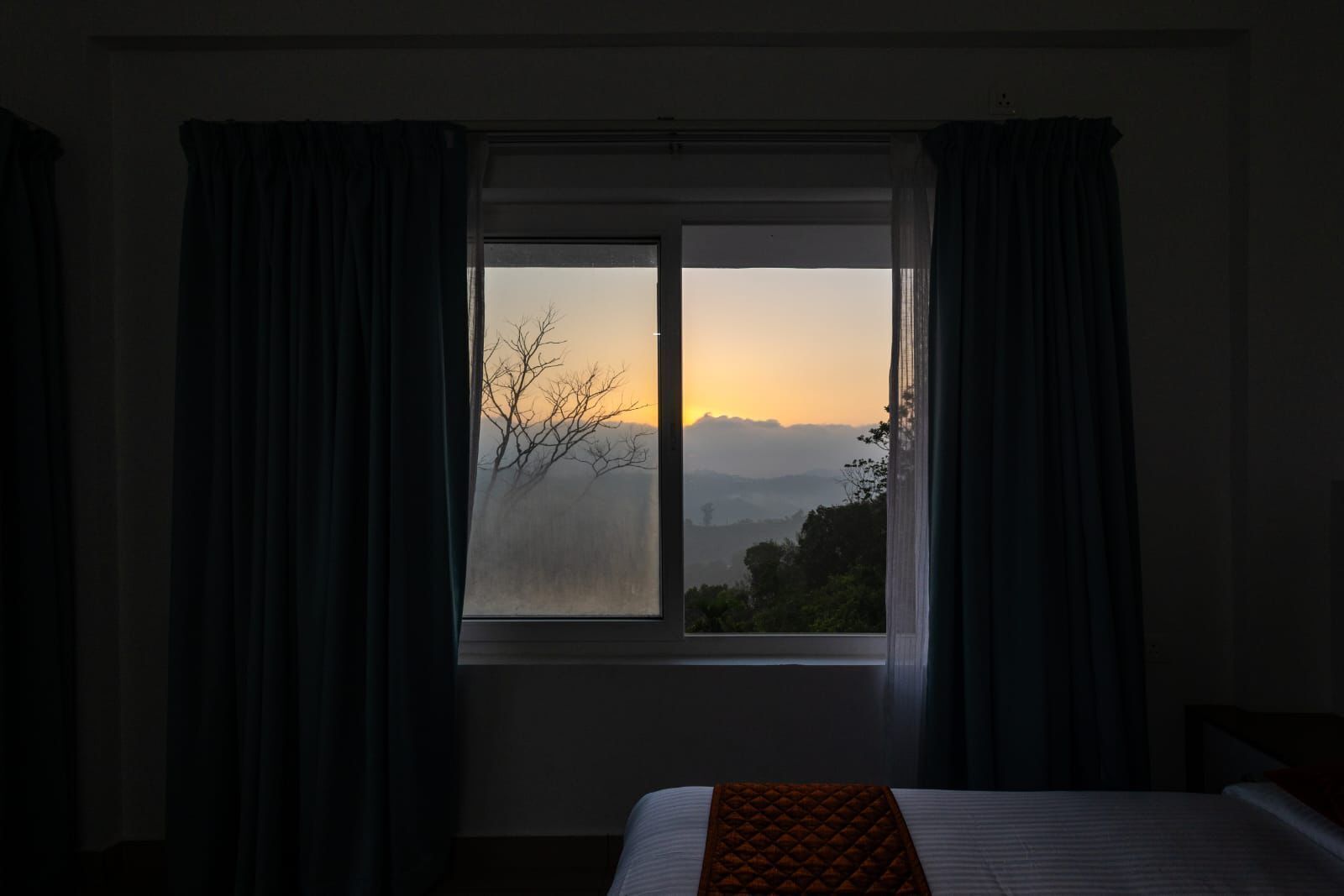 A room with a bed, a window, and curtains.