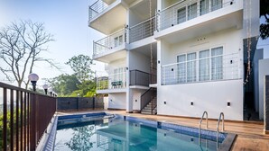 Un edificio moderno con piscina, balcones y una escalera.