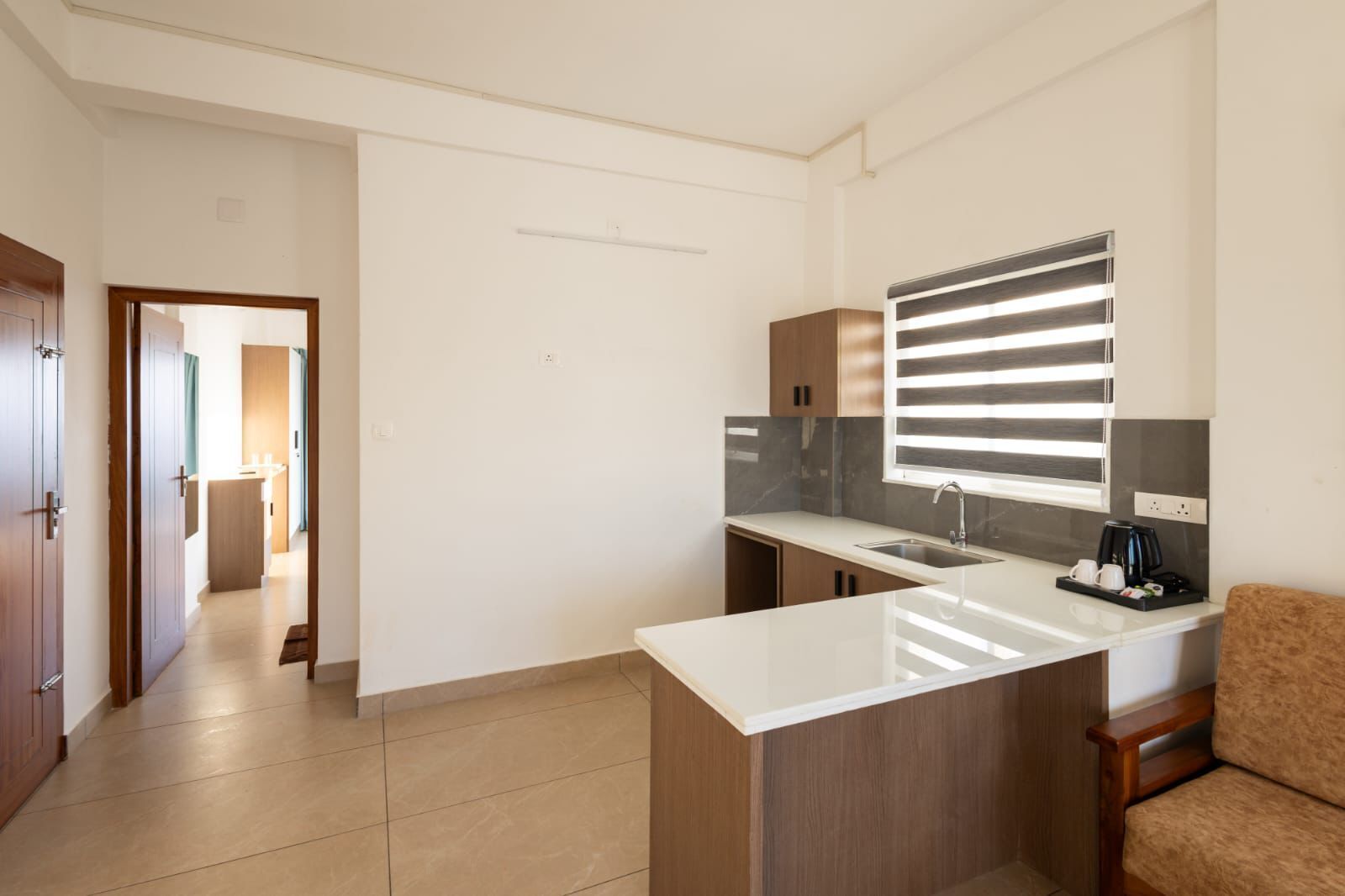 A modern kitchen with a white countertop, a built-in oven, and a window with blinds.