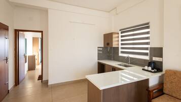 A modern kitchen with a white countertop, a built-in oven, and a window with blinds.