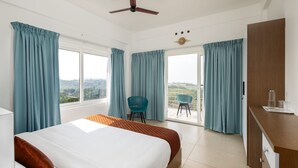A hotel room with a bed, a desk, a chair, and a balcony with a view. - Nithara Hills Resort (Peermade)