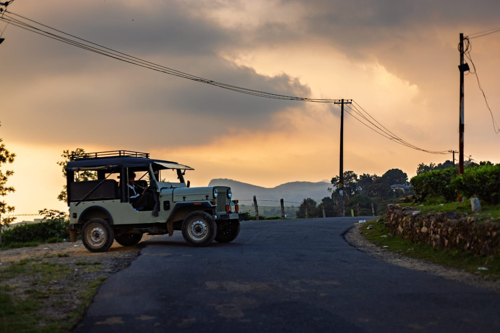 A vehicle on a rural road with a cloudy sky.