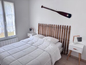 Ein Schlafzimmer mit einem Bett, einem Holzkopfstück, einem Nachttisch mit Lampe und einem Fenster mit Jalousien.