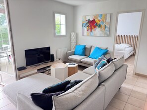 Ein modernes Wohnzimmer mit Sofa, Fernseher, Couchtisch und einem Gemälde an der Wand.
