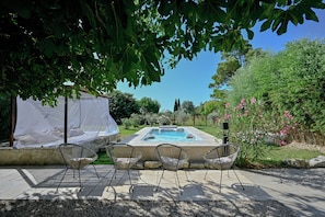 An outdoor hot tub area with chairs, a covered seating area, and a pool. - Charming, authentic farmhouse in the Camargue with a swim spa and pool (Arles)