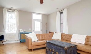 Una sala de estar con un sofá de cuero marrón, un baúl azul y un mueble pequeño azul.