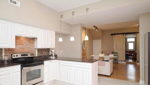 Een moderne keuken met witte kasten, een centraal eiland en hanglampen.