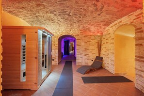 A spa area with a wooden sauna, a massage room, and a relaxation lounge with a view of the stone walls. - Reginella Garden View Studio with Shared Terrace, Wi-Fi, and Air Conditioning (Meta)