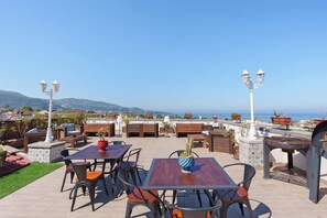 An outdoor patio with tables and chairs, a cactus centerpiece, and a view of the sea. - Reginella Garden View Studio with Shared Terrace, Wi-Fi, and Air Conditioning (Meta)