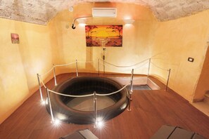 A hot tub with a rope barrier, wooden flooring, a painting of a sunset, and an air conditioning unit on the ceiling. - Reginella Garden View Studio with Shared Terrace, Wi-Fi, and Air Conditioning (Meta)