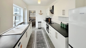 Eine moderne Küche mit weißen Schränken, einer schwarzen Arbeitsplatte und einem eingebauten Kühlschrank.