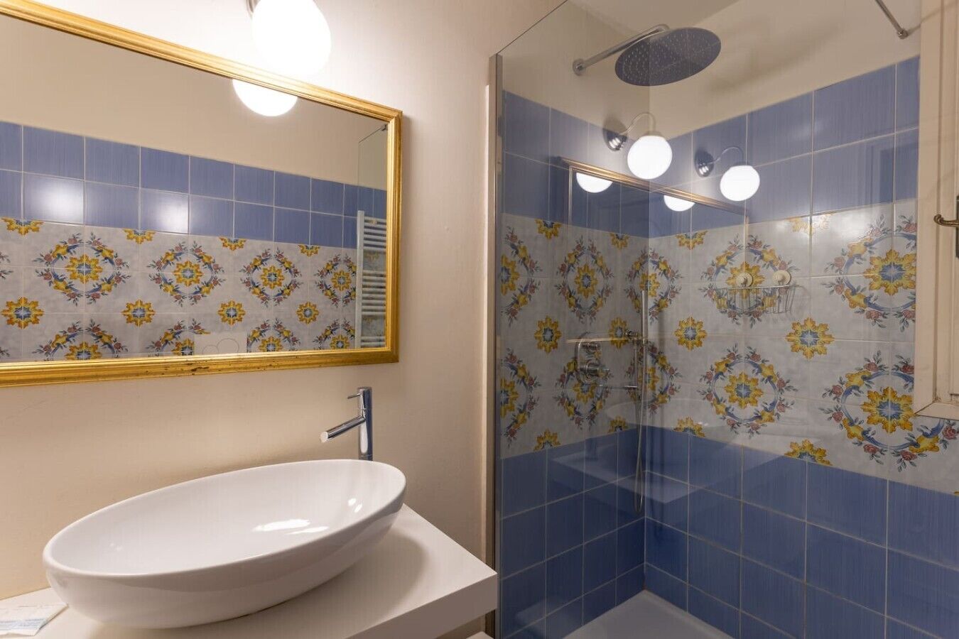 Une salle de bain avec un grand miroir, un lavabo et une douche aux carreaux bleus.