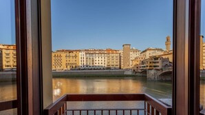 Blick vom Balkon auf einen Fluss mit Gebäuden und einem Turm im Hintergrund.