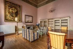 Ein Zimmer mit Kamin, einer Couch, einem Esstisch und einem Fernseher.