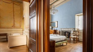 Une chambre à coucher avec un lit, une chaise, une cheminée et un lustre.
