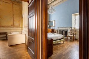 Une chambre à coucher avec un lit, une chaise, une cheminée et un lustre.