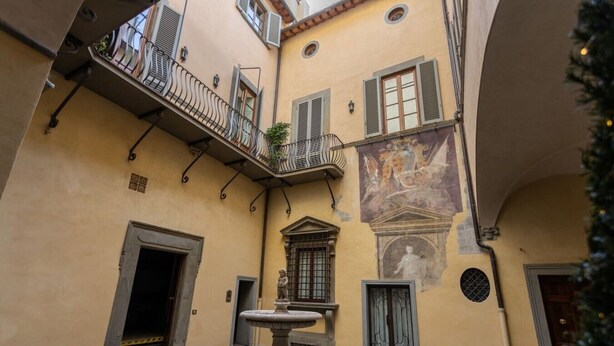Une cour avec une fontaine, une statue et une fresque murale.