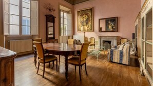 Une pièce comprenant une table à manger en bois, des chaises, une cheminée et un grand tableau accroché au mur.