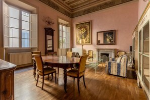 Une pièce comprenant une table à manger en bois, des chaises, une cheminée et un grand tableau accroché au mur.