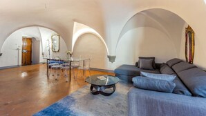 Een ruime woonkamer met een bank, een salontafel en een eettafel met stoelen.
