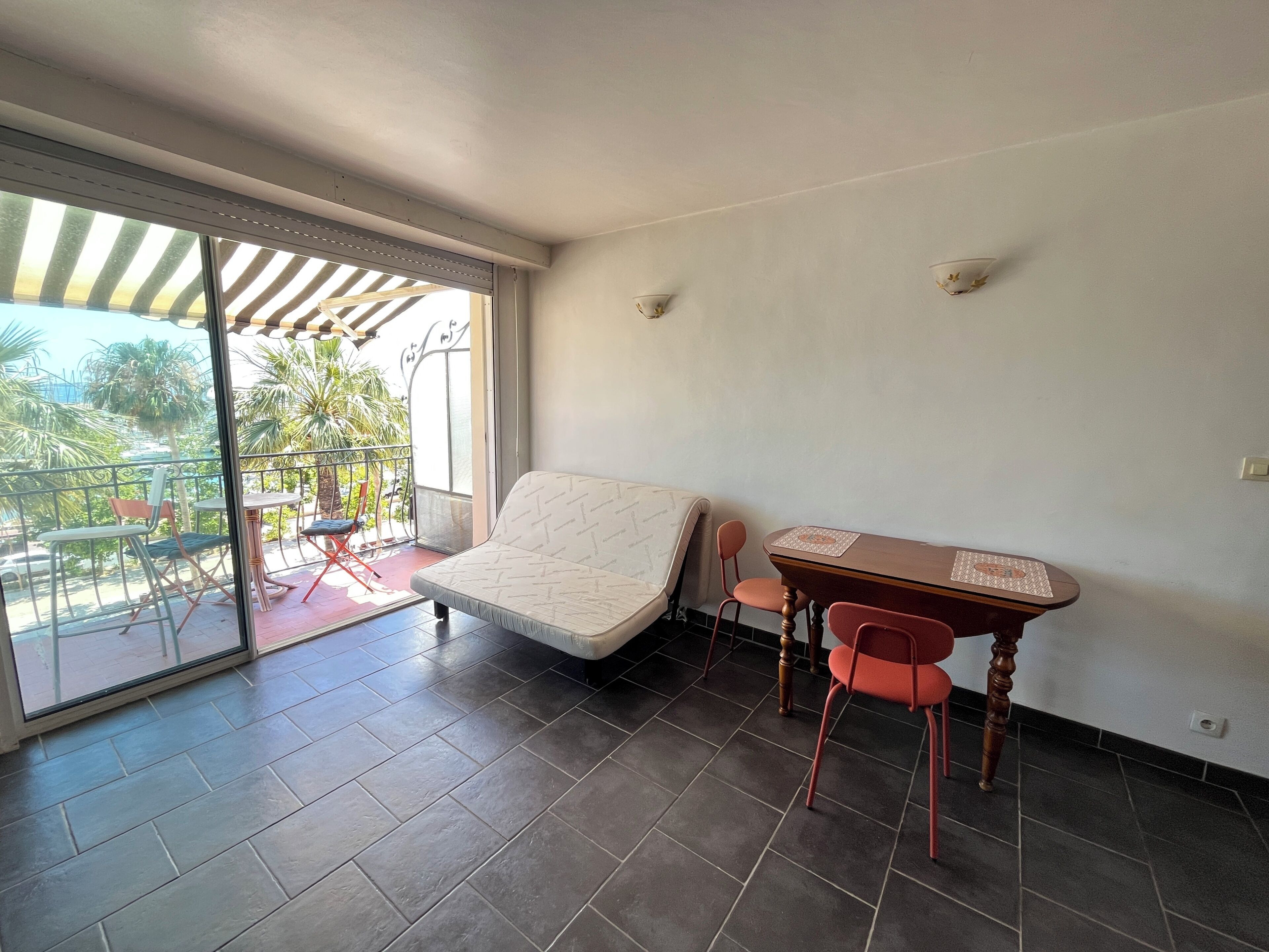 Un balcone con divano e poltrone, un tavolo e vista su palme.