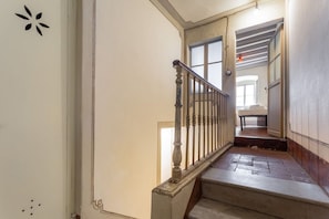 A staircase with a wooden handrail and a door leading to a room with a bed and a table. - Single Room in a Historic Building (Florence)