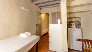 A small, compact room with a single bed, a white refrigerator, and a kitchenette area. - Single Room in a Historic Building (Florence)