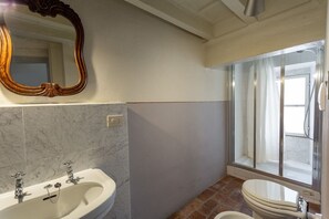 A bathroom with a marble sink, a toilet, and a shower area with a window. - Single Room in a Historic Building (Florence)