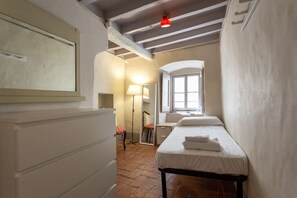 A narrow room with a bed, a desk, a chair, and a mirror. - Single Room in a Historic Building (Florence)