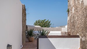 A narrow outdoor corridor with a tiled floor, a potted plant, a lantern, and a small seating area. - Apartment '2' with Shared Terrace and Wi-Fi (Vejer de la Frontera)