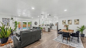 Una sala de estar moderna con sofá, mesa de comedor y plantas en macetas.