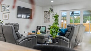 A living room with a reclining sofa, a flat-screen TV, and a potted plant. - Conveniently Located - S Lakeland Pool Home, Pet and Family Friendly (Lakeland)