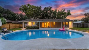 Una piscina residencial con una casa al fondo.